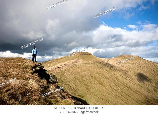 Female hiker hiking in mountains of Brecon Beacons national park with view of Pen Y Fan and Corn Du, Wales