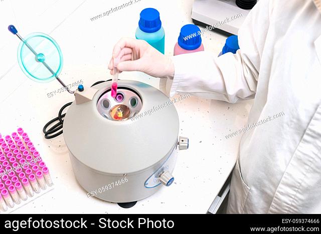 Researcher using laboratory equipment, putting sample tube in centrifuge machine to to do the lab test