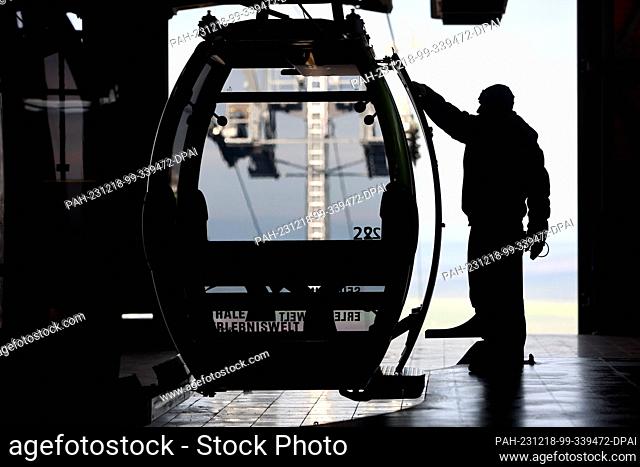 18 December 2023, Saxony-Anhalt, Thale: An employee of Seilbahnen Thale GmbH inspects a cable car gondola at the mountain station in Thale