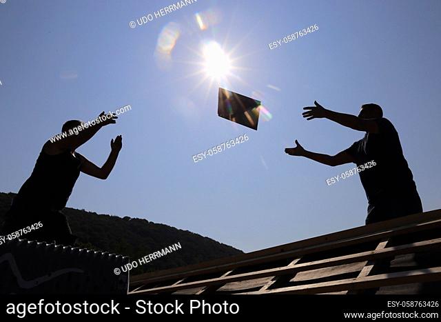 Silhouettes of roofers in the backlight