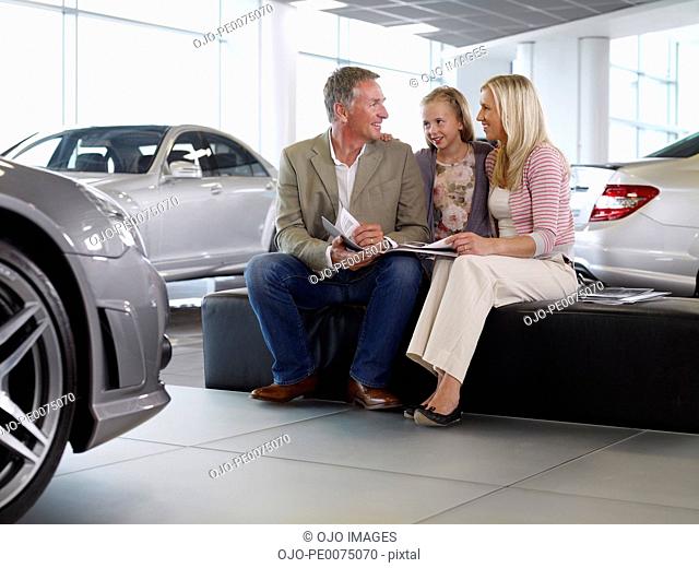 Family looking at brochure in automobile showroom