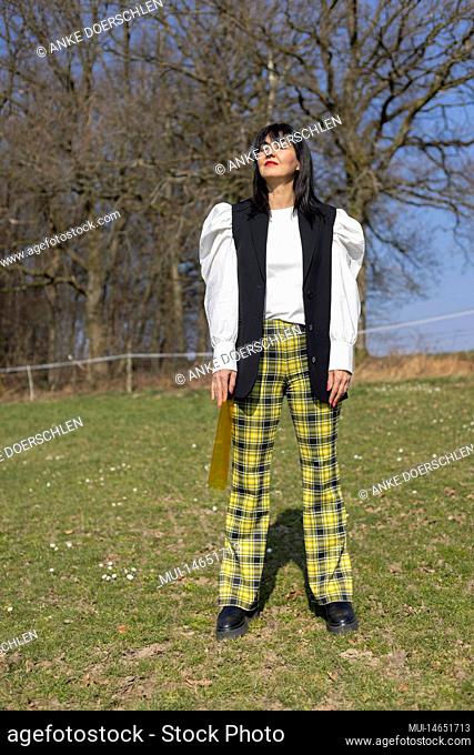 Fashionably dressed woman enjoying the sun on a meadow