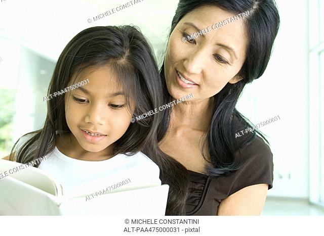 Mother and daughter reading book together, close-up