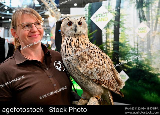 22 November 2023, Saxony, Leipzig: Petra Paetzold, falconer, stands with a Siberian eagle owl (Bubo bubo) at a stand for trips to the Saxon Vogtland at the...