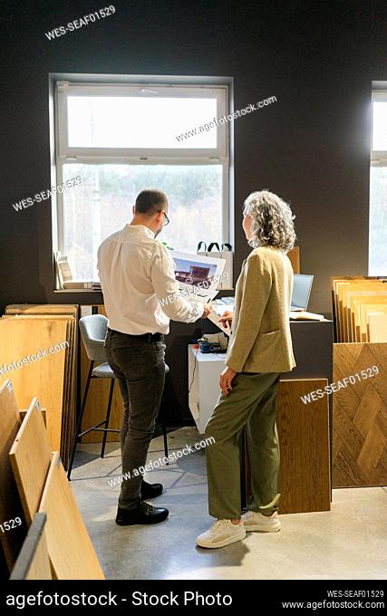 Two colleagues looking at printout of a house in architect's office