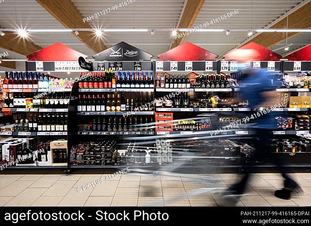 PRODUCTION - 15 December 2021, North Rhine-Westphalia, Kaarst: A man walks his shopping trolley past shelves of Sansibar and deluxe products in a Lidl store