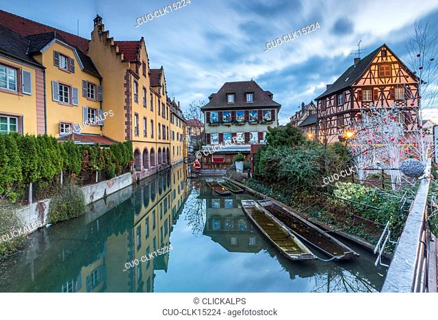 Dusk lights on houses reflected in river Lauch at Christmas Petite Venise, Colmar, Haut-Rhin department, Alsace, France, Europe