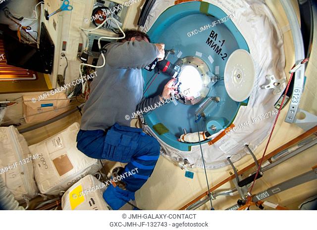 At a window in the Poisk Mini-Research Module 2 (MRM2), Russian cosmonaut Pavel Vinogradov, Expedition 36 commander, uses a digital still camera to photograph...
