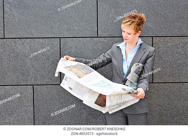 Geschäftsfrau liest unterwegs eine Zeitung bei Wind