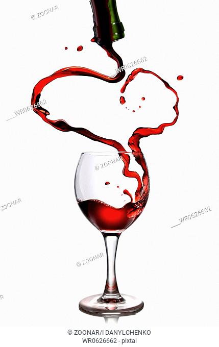 Red wine pouring in goblet from bottle in shape of heart