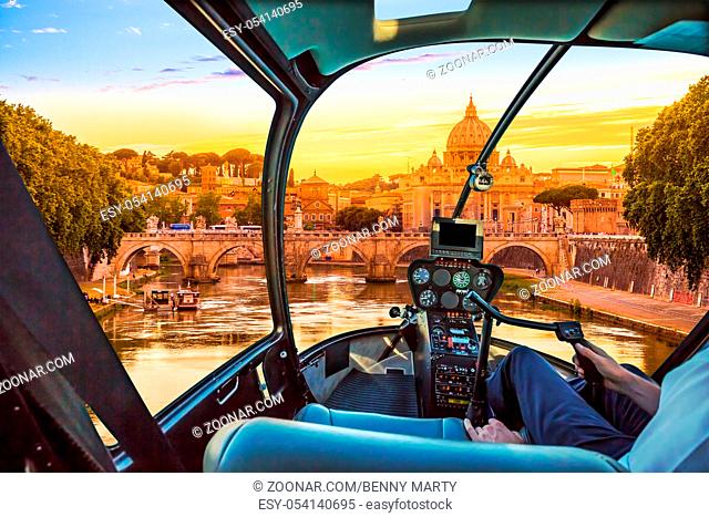 Rome at Sunset with San Pietro basilica, Sant'Angelo bridge and Tevere river in Roma, Italy. Helicopter cockpit with pilot arm and control console inside the...