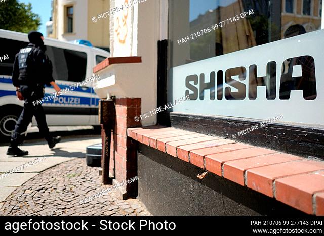 06 July 2021, Saxony, Leipzig: A policeman walks along in front of a shisha bar. Several shisha bars and kebab joints were searched in the city