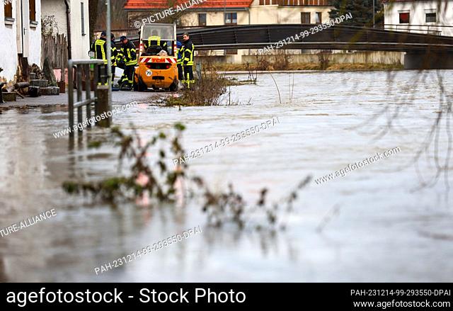14 December 2023, Baden-Württemberg, Riedlingen: Firefighters use sandbags to build a dam on the Danube to protect houses in Riedlingen from flooding