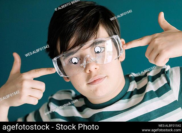 Close-up of boy wearing eyewear with googly eyes against wall