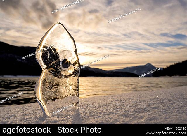 Ice during sunset on the shore of Walchensee lake in the Bavarian foothills of the Alps with sun rays