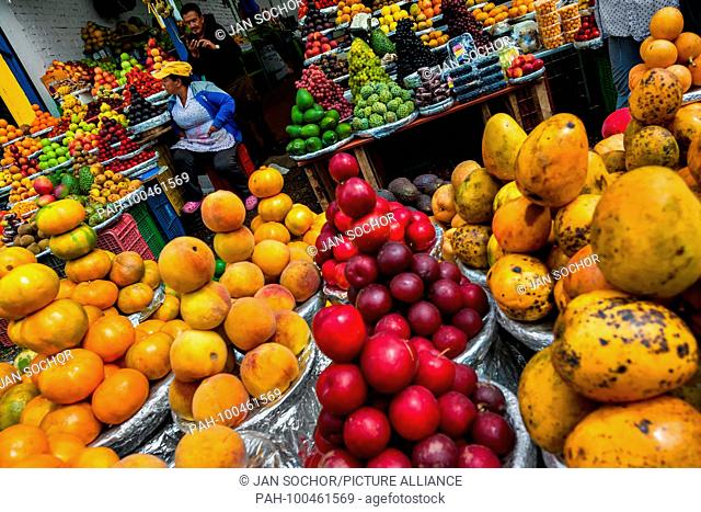 A Colombian vendor sits on the box behind the piles of fruits at the market of Paloquemao in Bogota, Colombia, 25 November 2017. | usage worldwide