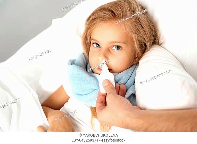 sickness and health care concept, dad giving nasal drops to his daughter
