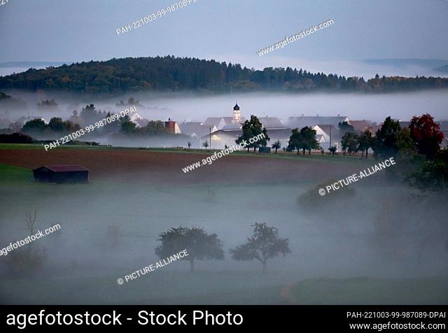 03 October 2022, Baden-Wuerttemberg, Unlingen: Fog has formed around the church of St. Nicholas in Dietelhofen in the morning shortly before sunrise Photo:...