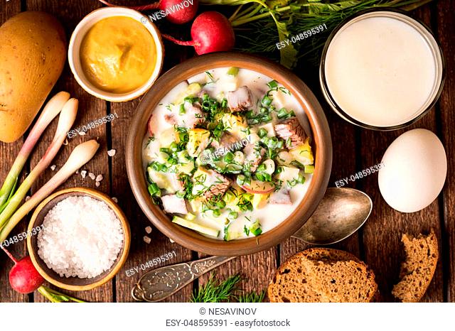 Okroshka. Traditional Russian summer cold yogurt soup in bowl on wooden background. Top view