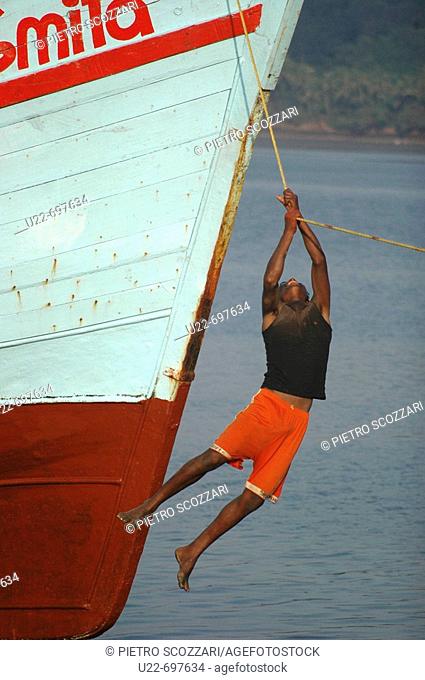 Chapora, Goa India: a young fisherman hanging on a cord of his boat