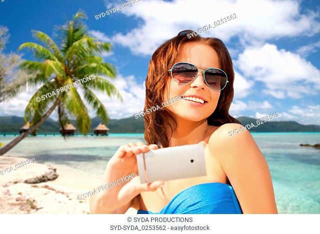 woman taking selfie by smartphone on beach