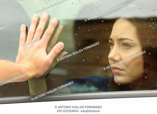 Couple saying goodbye before car travel holding hands through the window