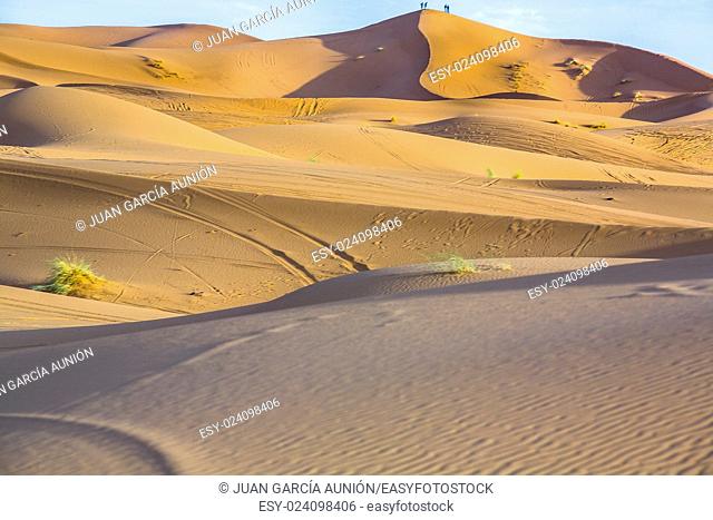 People admire the sunrise from a hill. Several sand hill at Erg Chebbi in the Sahara desert. Ers are large dunes formed by wind-blown sand