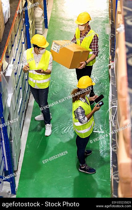 Top view Interracial team Asian African Caucasian work check goods use clipboard barcode scanner in distribution center. All wear face mask prevent from...