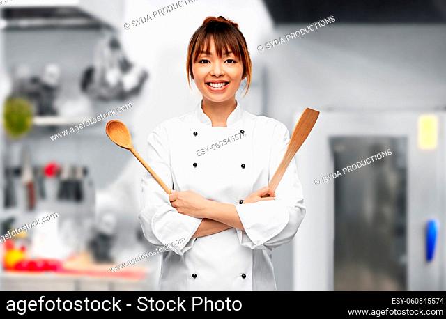 happy female chef with wooden spoon on kitchen
