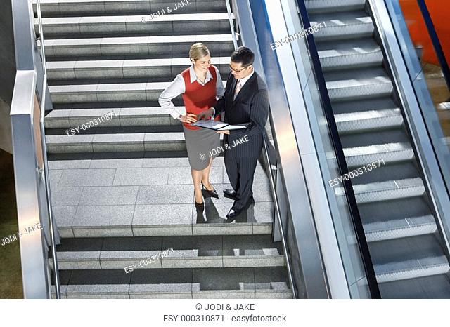 Businessman and businesswoman conversing on stairs elevated view