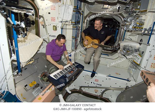 NASA astronaut Dan Burbank, Expedition 30 commander, plays a guitar, while Russian cosmonaut Anton Shkaplerov, flight engineer