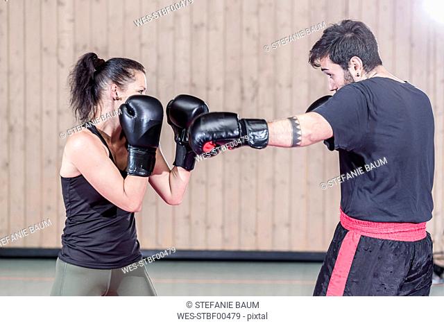 Female boxer sparring with coach in sports hall
