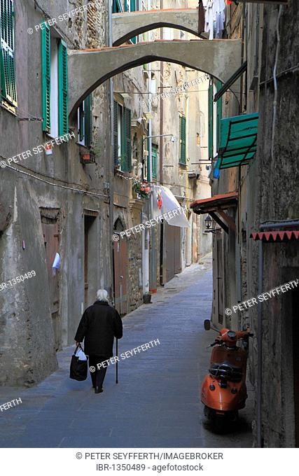 Woman dressed in black walking through an alleyway in the historic town centre of Ventimiglia, province of Imperia, Liguria region, Riviera dei Fiori
