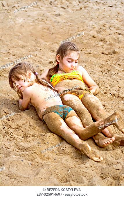 Two girls lying on the sand near the river