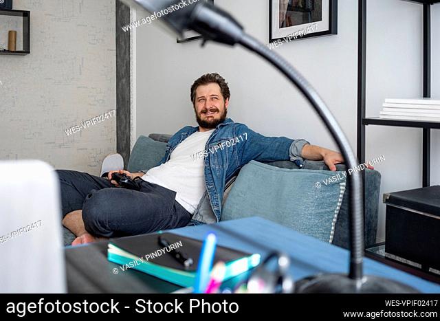 Man sitting on couch and playing video game looking up