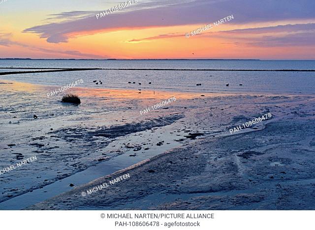 The warm and colourful light of the morning sun illuminates the Wadden Sea and the sky near the village Nebel on the island Amrum, 2 May 2018 | usage worldwide