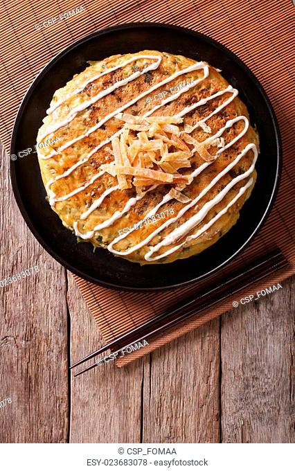 Japanese okonomiyaki on a wooden table. vertical top view