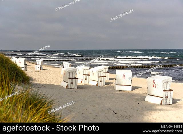 View over the deserted beach with white beach chairs and moving Baltic Sea with whitecaps in the early morning in summer