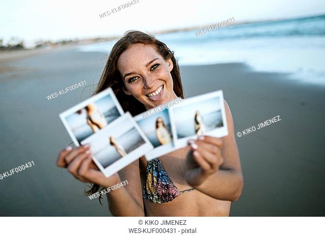 Young woman showing instant photos on the beach