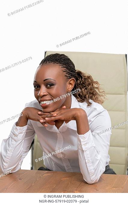 African business woman sitting at her desk and smiling isolated on white background
