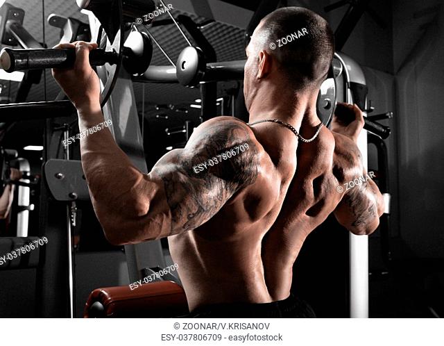 Athlete muscular bodybuilder training back on simulator in the gym