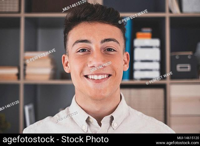 Portrait of one young and happy cheerful man smiling looking at the camera having fun. Headshot of male person working at home in the office