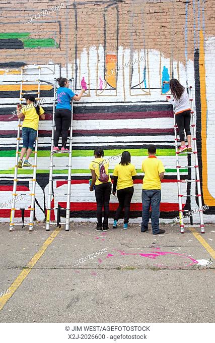 Detroit, Michigan - High school volunteers paint a mural on the wall of the Detroit Nipple Works, a manufacturer of pipefitting supplies