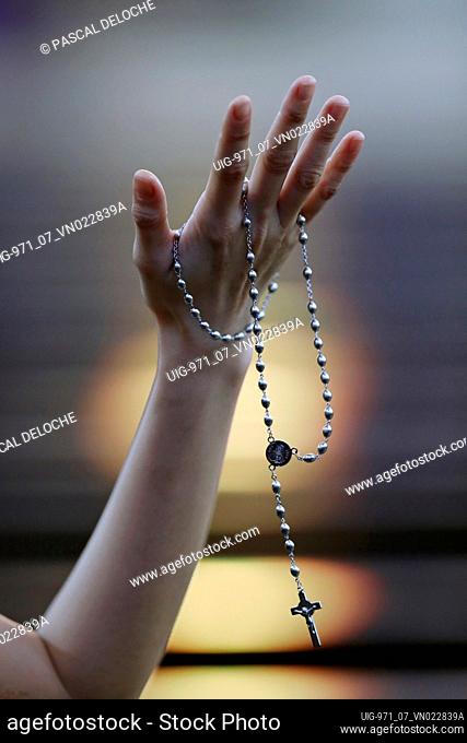 Hand of a woman holding a rosary or crucifix while praying, Christian daily devotional of a worshiper of God the Savior. Hue. Vietnam