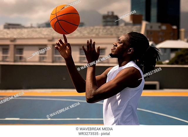 Basketball player balancing ball on finger at basketball court