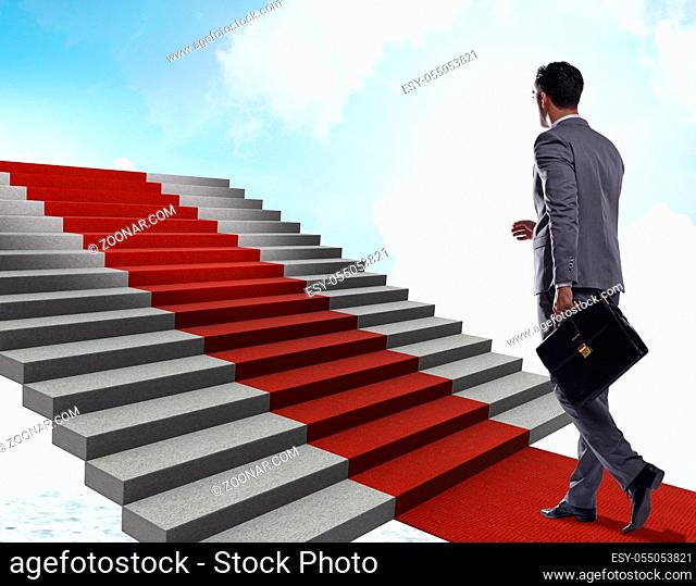 The young businessman climbing stairs and red carpet into sky