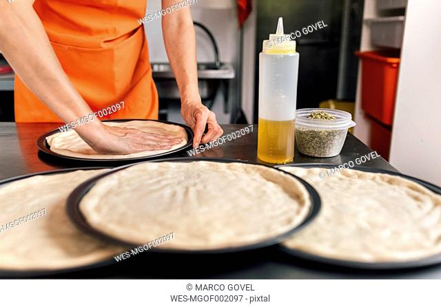 Woman's hands preparing pizza dough, partial view