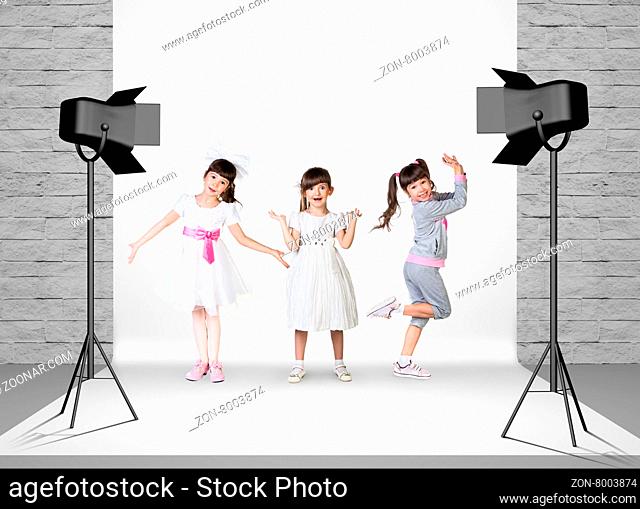 Little girls in photo studio room with white cloth and spotlights