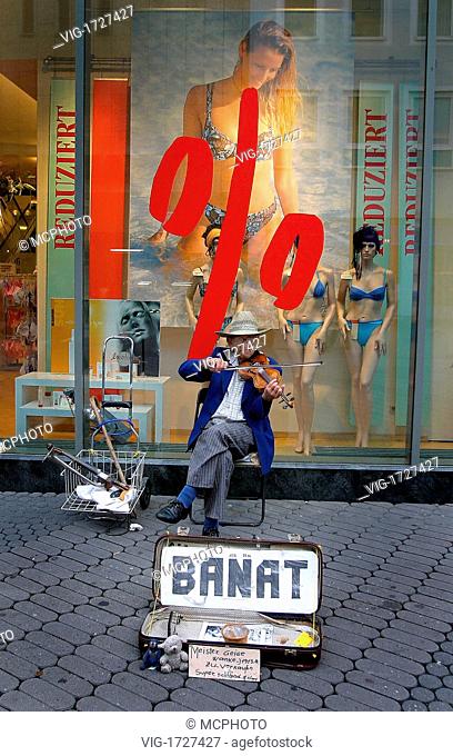 Road musician from the Banat in front of a shop window with sale - 01/01/2009