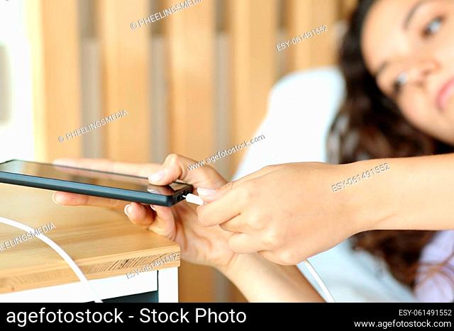 Close up of a woman connecting usb charger on smart phone in a bedroom
